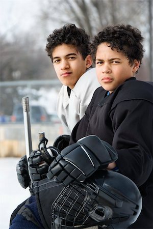 Two boys in ice hockey uniforms sitting on ice rink sidelines looking. Foto de stock - Super Valor sin royalties y Suscripción, Código: 400-04471038