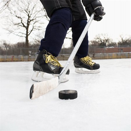 preteen feet plays - Boy in ice hockey uniform skating on ice rink moving puck. Stock Photo - Budget Royalty-Free & Subscription, Code: 400-04471031