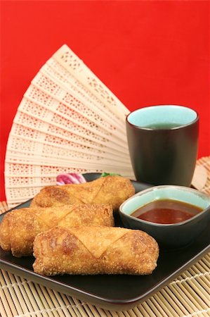 simsearch:400-05350825,k - Crispy golden egg rolls served with tea against a red background.  Vertical with room for text. Foto de stock - Royalty-Free Super Valor e Assinatura, Número: 400-04485051
