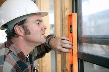 A horizontal view of a carpenter checking a newly installed window to see if it's level.  Authentic and accurate content. Stock Photo - Budget Royalty-Free & Subscription, Code: 400-04485130