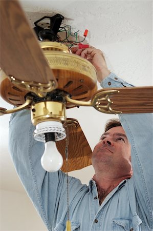 An electrician disconnecting the wires of an old ceiling fan.  Fan was installed without ceiling box - a code violation.  Model is a licensed master electrician, actually performing the work. Stock Photo - Budget Royalty-Free & Subscription, Code: 400-04485174