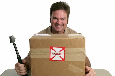 A delivery man with a package marked fragile.  He is about to hit it with a hammer. Stock Photo - Budget Royalty-Free & Subscription, Code: 400-04485206