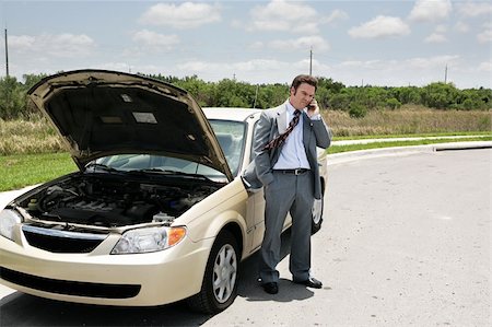 A businessman with a flat tire on the phone with the auto club. Stock Photo - Budget Royalty-Free & Subscription, Code: 400-04485207