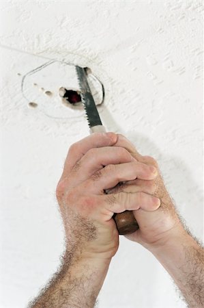 An electrician with using a saw to cut a hole in the ceiling to put a fan box. Work is being performed by a licensed master electrician. Stock Photo - Budget Royalty-Free & Subscription, Code: 400-04485311