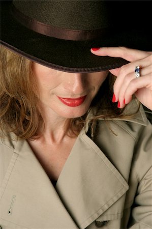 A beautiful, sexy woman in a trenchcoat and fedora hat.  Her eyes are concealed beneath the brim of the hat. Photographie de stock - Aubaine LD & Abonnement, Code: 400-04485694