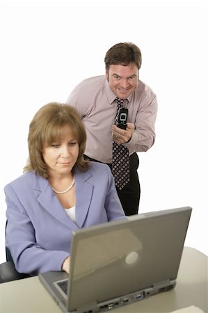 A man with a camera phone taking pictures of a coworker's computer screen behind her back.  Isolated on white with focus on man. Photographie de stock - Aubaine LD & Abonnement, Code: 400-04486273