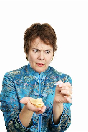 A woman upset over a bad fortune she got in her fortune cookie.  Isolated on white. Stock Photo - Budget Royalty-Free & Subscription, Code: 400-04486597