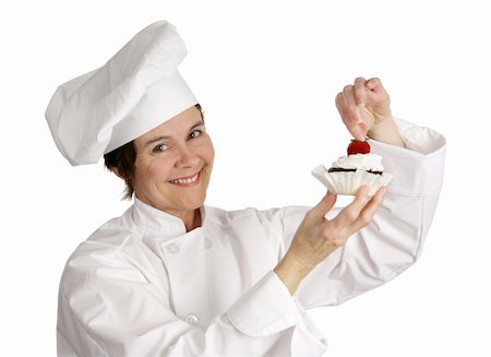 female pastry chef - A pastry chef putting a strawberry on the top of a cheesecake tart.  Isolated on white. Foto de stock - Super Valor sin royalties y Suscripción, Código: 400-04486603