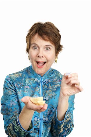 A pretty woman in a chinese blouse opening her fortune cookie with a surprised expression. Stock Photo - Budget Royalty-Free & Subscription, Code: 400-04486636