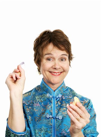 A pretty woman in a chinese blouse excited to find a fortune inside her cookie.  Isolated on white. Stock Photo - Budget Royalty-Free & Subscription, Code: 400-04486637