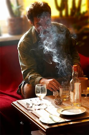 Morning. Man sits at table and smoks cigatrett, near stands  bottle of vodka and glass Stock Photo - Budget Royalty-Free & Subscription, Code: 400-04489261