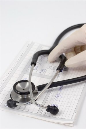 simsearch:400-07976201,k - Stethoscope on a medical record. In the background a hand with medical rubber glove. Focus on the foreground on the bows of the stethoscope. Stock Photo - Budget Royalty-Free & Subscription, Code: 400-04480444