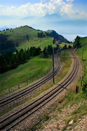 The winding tram tracks on Rigi mountain in Switzerland.  In the distance through the haze and clouds is a lake and more Alps. Stock Photo - Budget Royalty-Free & Subscription, Code: 400-04495704