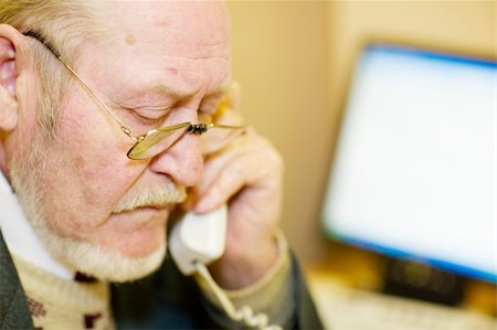 simsearch:400-04504842,k - Mature businessman talking on the phone and checking out a document on his computer monitor. Photographie de stock - Aubaine LD & Abonnement, Code: 400-04495754