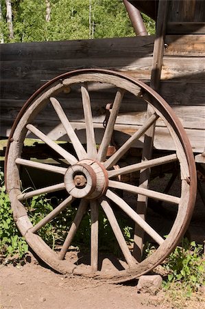 simsearch:400-05102252,k - An old, weathered wagon wheel in the American West is an example of the rustic charm of the country. This wheel is covered with an iron strip for durability. Stock Photo - Budget Royalty-Free & Subscription, Code: 400-04497060