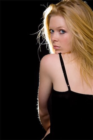 simsearch:400-04498992,k - Attractive woman with long blond hair and blue eyes with serious expression wearing black looking over bare shoulder Photographie de stock - Aubaine LD & Abonnement, Code: 400-04498990