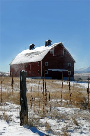 estilo - Rustic red wooden barn sits in a field of white.  Pasture has snow, fence and stile.  Snow blows from roof.  Blue skies. Stock Photo - Budget Royalty-Free & Subscription, Code: 400-04499077