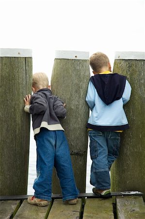 Two boys looking though a couple of poles, to see what's beyond. On white background. Fotografie stock - Microstock e Abbonamento, Codice: 400-04493314