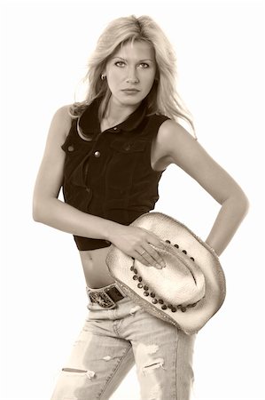 simsearch:400-04502103,k - Beautiful blond woman holding straw cowboy hat wearing a brown vest and faded ripped jeans on white Stock Photo - Budget Royalty-Free & Subscription, Code: 400-04500091