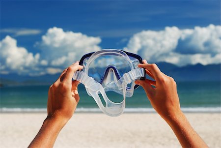 simsearch:6109-06195375,k - Snorkel equipment in hands against beach and sky Fotografie stock - Microstock e Abbonamento, Codice: 400-04502041