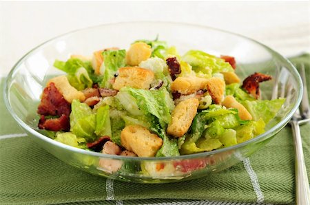 salada caesar - Fresh caesar salad with croutons and bacon bits served in a glass bowl Foto de stock - Royalty-Free Super Valor e Assinatura, Número: 400-04514063