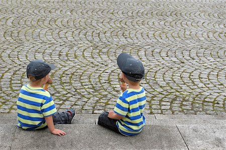 Two twin boys in matching clothes eating ice creams, sitting next to a cobblestone pavement. Stock Photo - Budget Royalty-Free & Subscription, Code: 400-04515338