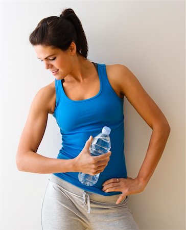 Portrait of woman in fitness attire flexing arm muscle holding water bottle and smiling. Stock Photo - Budget Royalty-Free & Subscription, Code: 400-04510252