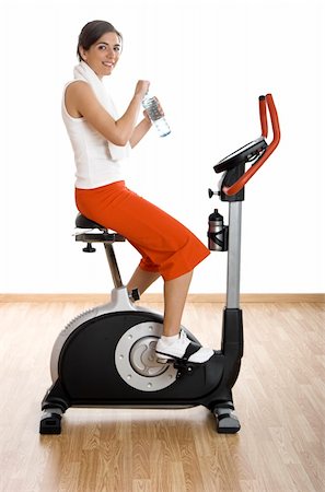simsearch:400-04027186,k - Young woman training on exercise bike at the gym and drinking water Stockbilder - Microstock & Abonnement, Bildnummer: 400-04510367