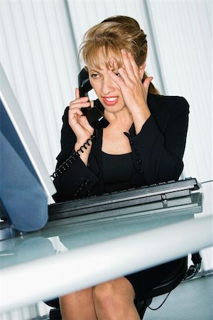 Caucasian businesswoman with hand to head and frustrated expression at computer desk on telephone. Stock Photo - Budget Royalty-Free & Subscription, Code: 400-04512361