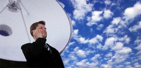 Successful businessman with cell phone in front of a huge satellite dish Stock Photo - Budget Royalty-Free & Subscription, Code: 400-04512811