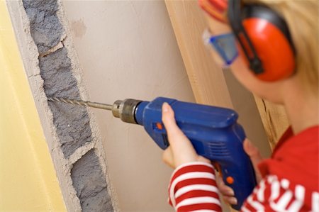 drilling wall - Do it yourself concept - woman drilling a hole into a jagged wall Stock Photo - Budget Royalty-Free & Subscription, Code: 400-04513382