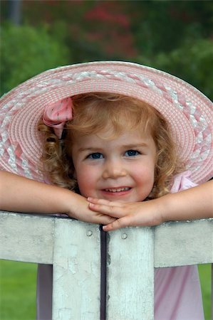 rosy cheeks - Young girl leans her chin on her hands.  She is resting on a white, wooden garden gate.  She has on a light pink dress and wide, brimmed hat. Stock Photo - Budget Royalty-Free & Subscription, Code: 400-04513537