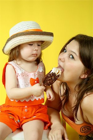 Two pretty sisters are eating ice-cream on yellow background Stock Photo - Budget Royalty-Free & Subscription, Code: 400-04527552