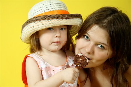 Two pretty sisters are eating ice-cream on yellow background Stock Photo - Budget Royalty-Free & Subscription, Code: 400-04527553