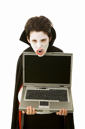Boy dressed as a vampire for Halloween, holding a computer with a message on it.  Blank space ready for your text.  Isolated on white. Photographie de stock - Aubaine LD & Abonnement, Code: 400-04527978