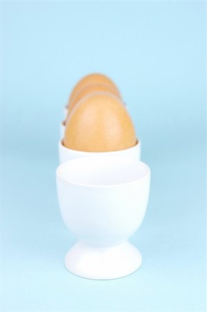 Hard boiled eggs and egg cups isolated against a blue background Stock Photo - Budget Royalty-Free & Subscription, Code: 400-04528033