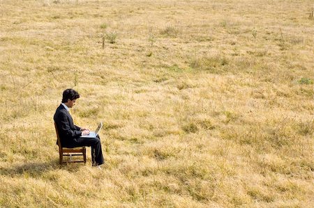 A young business man working on a laptop in the middle of a dry field. Stock Photo - Budget Royalty-Free & Subscription, Code: 400-04528135