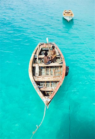 Two mischievous young boys play around on a fishing boat which is floating on stunning turquoise waters in the Cape Verde islands. Foto de stock - Super Valor sin royalties y Suscripción, Código: 400-04523156