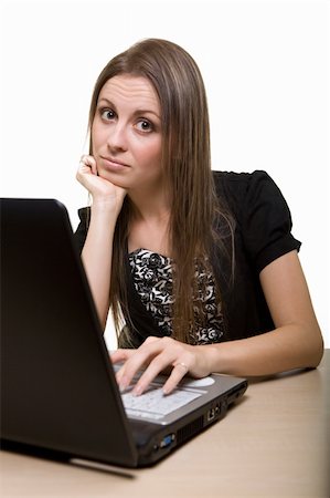 Attractive young brunette woman in business suit sitting at a desk typing on a computer keyboard and looking at camera with bored expression Stock Photo - Budget Royalty-Free & Subscription, Code: 400-04523261