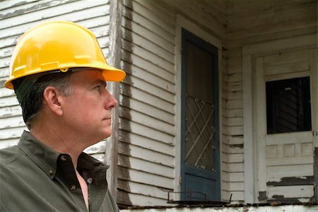 A man in a hard hat looking at an old rundown house. Stock Photo - Budget Royalty-Free & Subscription, Code: 400-04535266