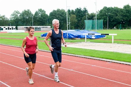 Senior couple running together on a track in a stadium. Fotografie stock - Microstock e Abbonamento, Codice: 400-04536201