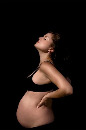 Pregnant female with a burnished gold and copper tint to her skin wearing a black bra and pants,  over black background. Stock Photo - Budget Royalty-Free & Subscription, Code: 400-04536295