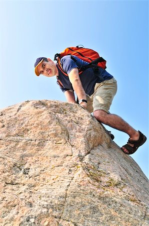 Middle aged man with backpack climbing a rock Stock Photo - Budget Royalty-Free & Subscription, Code: 400-04538152