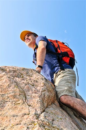 Middle aged man with backpack climbing a rock Stock Photo - Budget Royalty-Free & Subscription, Code: 400-04538153