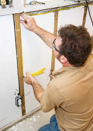 simsearch:400-04494971,k - Electrician installing wiring in an interior wall.   Authentic and accurate content depiction in accordance with industry code and safety standards. Stock Photo - Budget Royalty-Free & Subscription, Code: 400-04539164