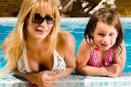 Young blond girl and her sister enjoying the sun in and around the swimming pool Stock Photo - Budget Royalty-Free & Subscription, Code: 400-04531115