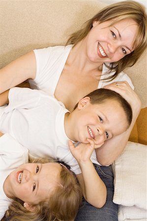Woman and kids in white shirts laying on the sofa laughing Stock Photo - Budget Royalty-Free & Subscription, Code: 400-04531142