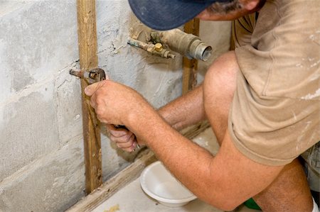 Plumber using channel-lock pliers to attach a nut to a water pipe. He has a bowl beneath to catch any remaining water.   Authentic and accurate content depiction. Fotografie stock - Microstock e Abbonamento, Codice: 400-04532199