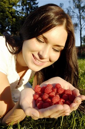 Beautiful young girl smiling holds fresh raspberries in hands (outdoors) Stock Photo - Budget Royalty-Free & Subscription, Code: 400-04545448