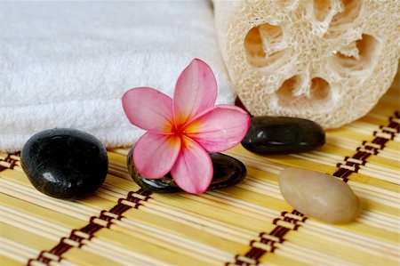simsearch:400-05663148,k - Frangipani and plumerias and black massage stones placed on bamboo mate at spa. Photographie de stock - Aubaine LD & Abonnement, Code: 400-04546870